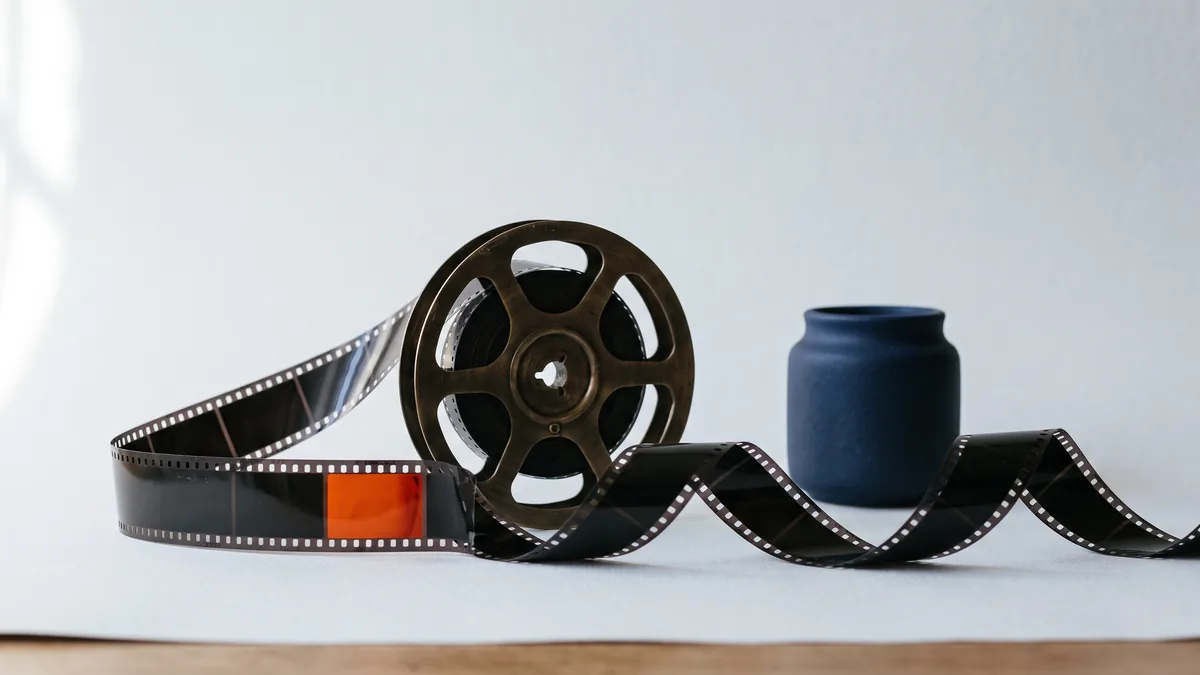 Film reel with a strip of film curling across the table, the cover image for 7 Tips for YouTube SEO & AIO (Updated 2026)