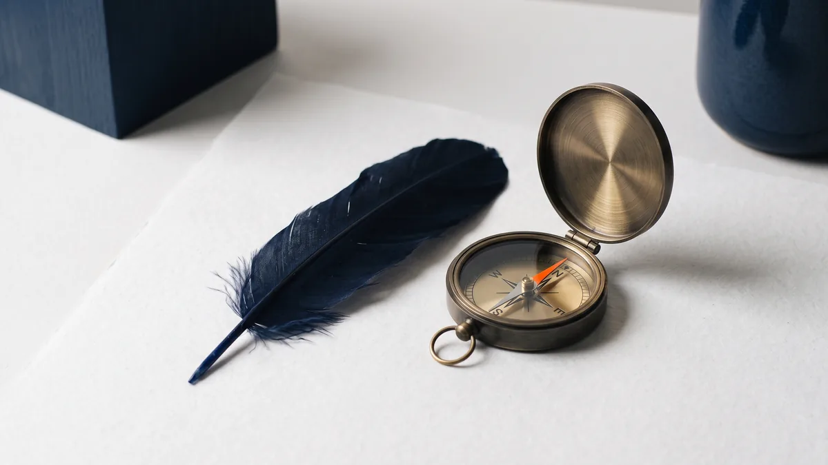 Raven feather beside a brass pocket compass, the cover image for Alternatives to Raven Tools Rank Tracker SEO Tool