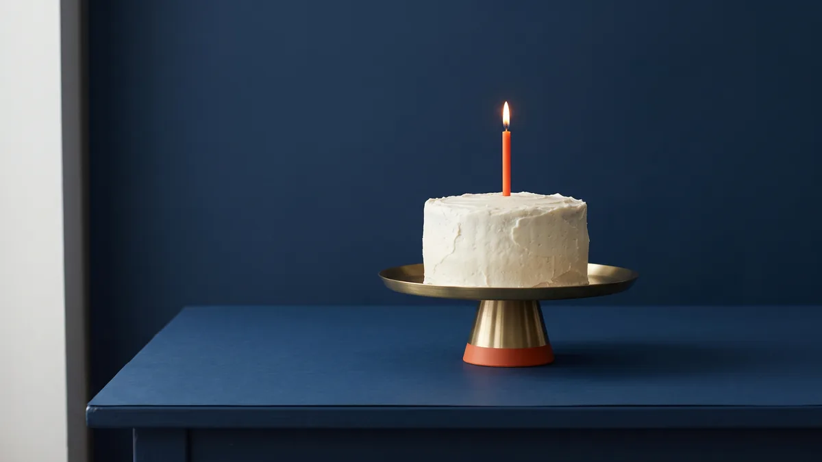 Small birthday cake with a single orange candle, the cover image for Happy Birthday Android