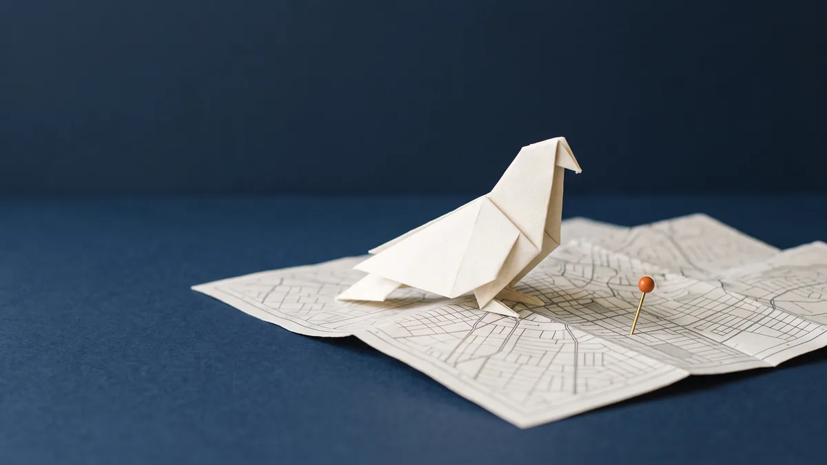 Origami pigeon perched on a folded paper street map, the cover image for Pigeon: Google’s Newest Algorithm Update